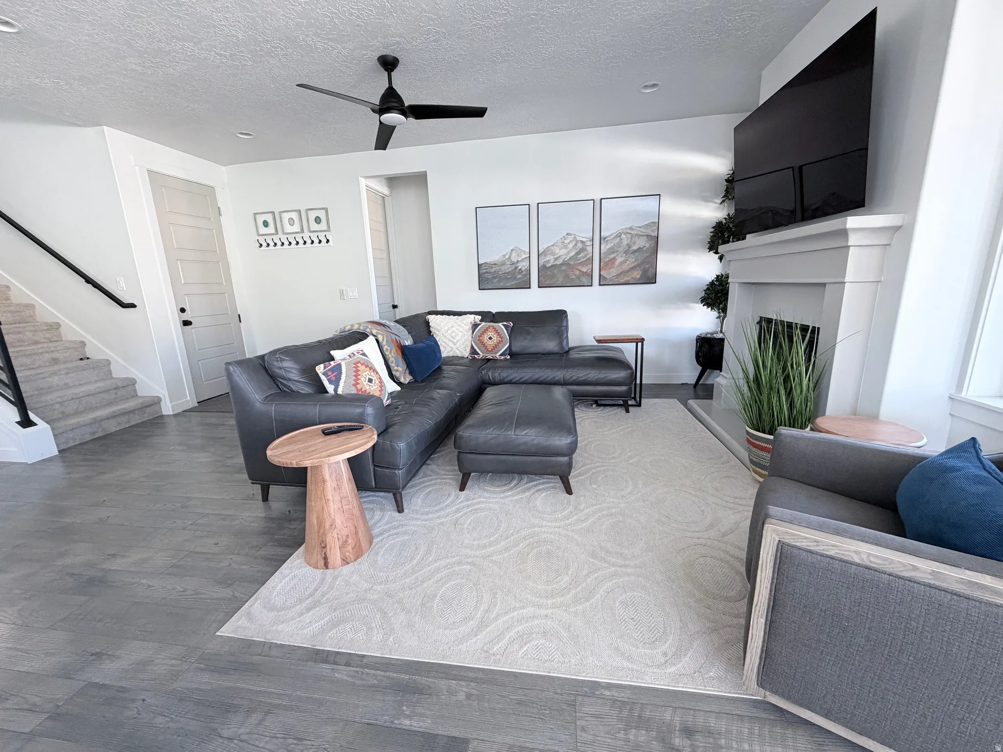 Living area with a textured ceiling, stairs, a ceiling fan, fireplace, Italian leather sofa and ottoman, LG TV