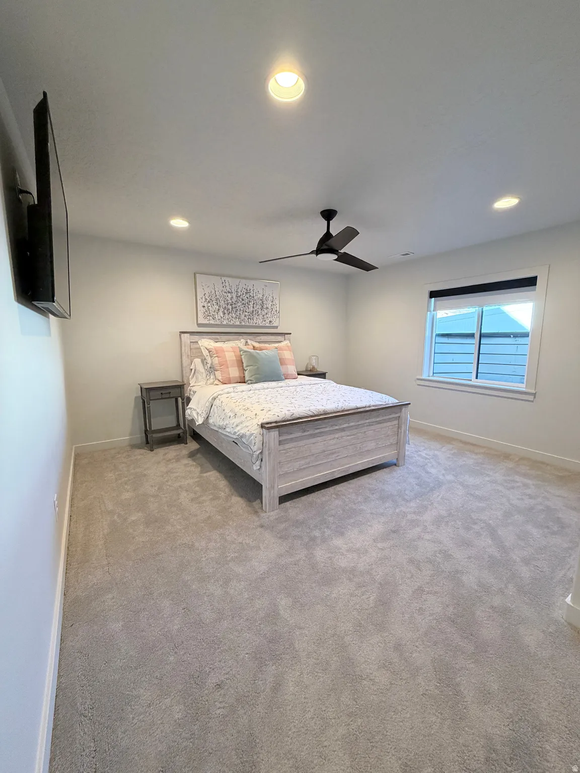 Bedroom with a ceiling fan, light carpet, and recessed lighting along with queen size bed with bedding and nightstands