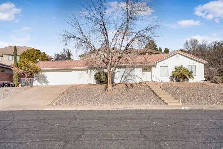 View of front of home featuring driveway, a tiled roof, an attached garage, and stucco siding