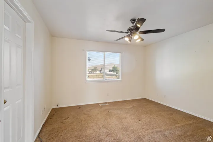 Empty room featuring light colored carpet and ceiling fan