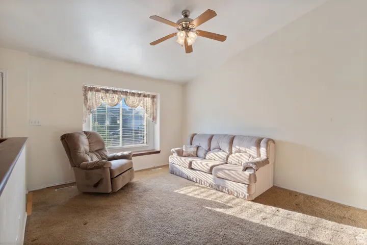 Carpeted living room featuring lofted ceiling and a ceiling fan