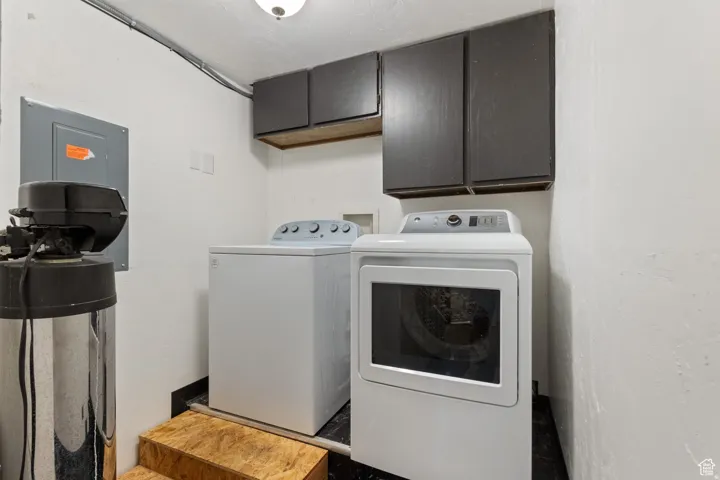 Laundry area featuring washing machine and clothes dryer, cabinet space, and electric panel