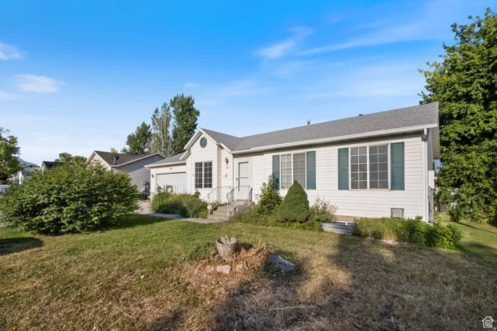 Ranch-style house featuring a front lawn, an attached garage, and roof with shingles