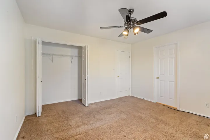 Unfurnished bedroom with a ceiling fan, light colored carpet, and a closet