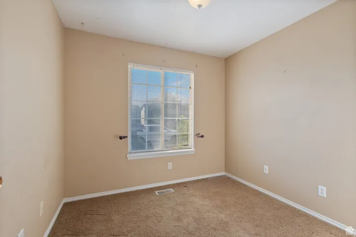 Unfurnished room featuring light carpet and baseboards
