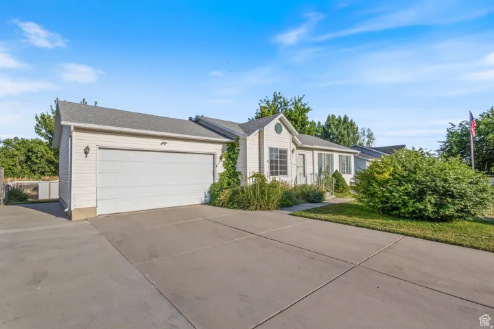 Ranch-style home with concrete driveway, an attached garage, and roof with shingles