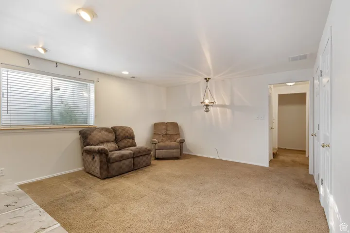 Sitting room with light colored carpet and recessed lighting