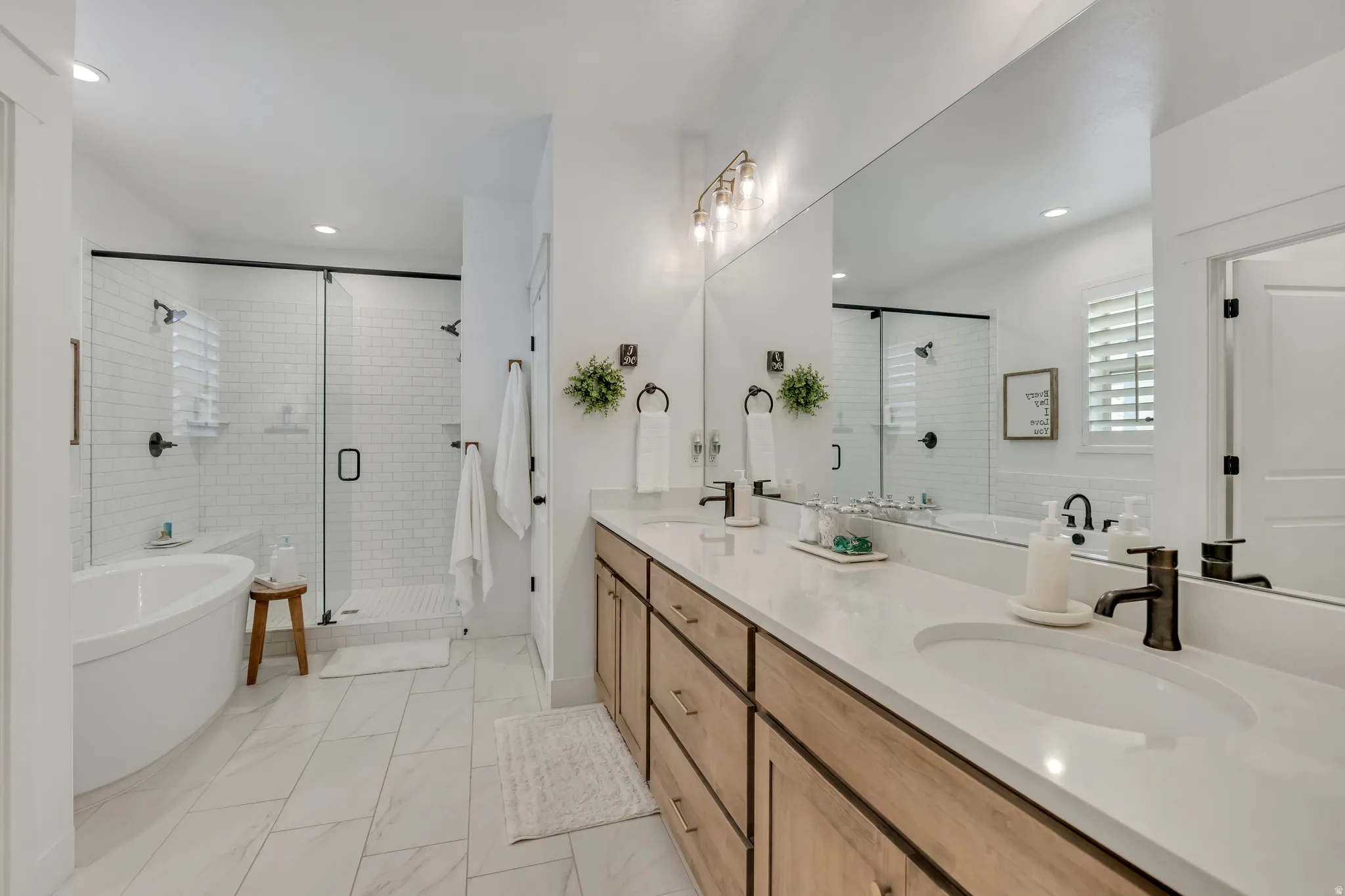 Primary Bathroom with a freestanding tub, a stall shower, double vanity, tile flooring