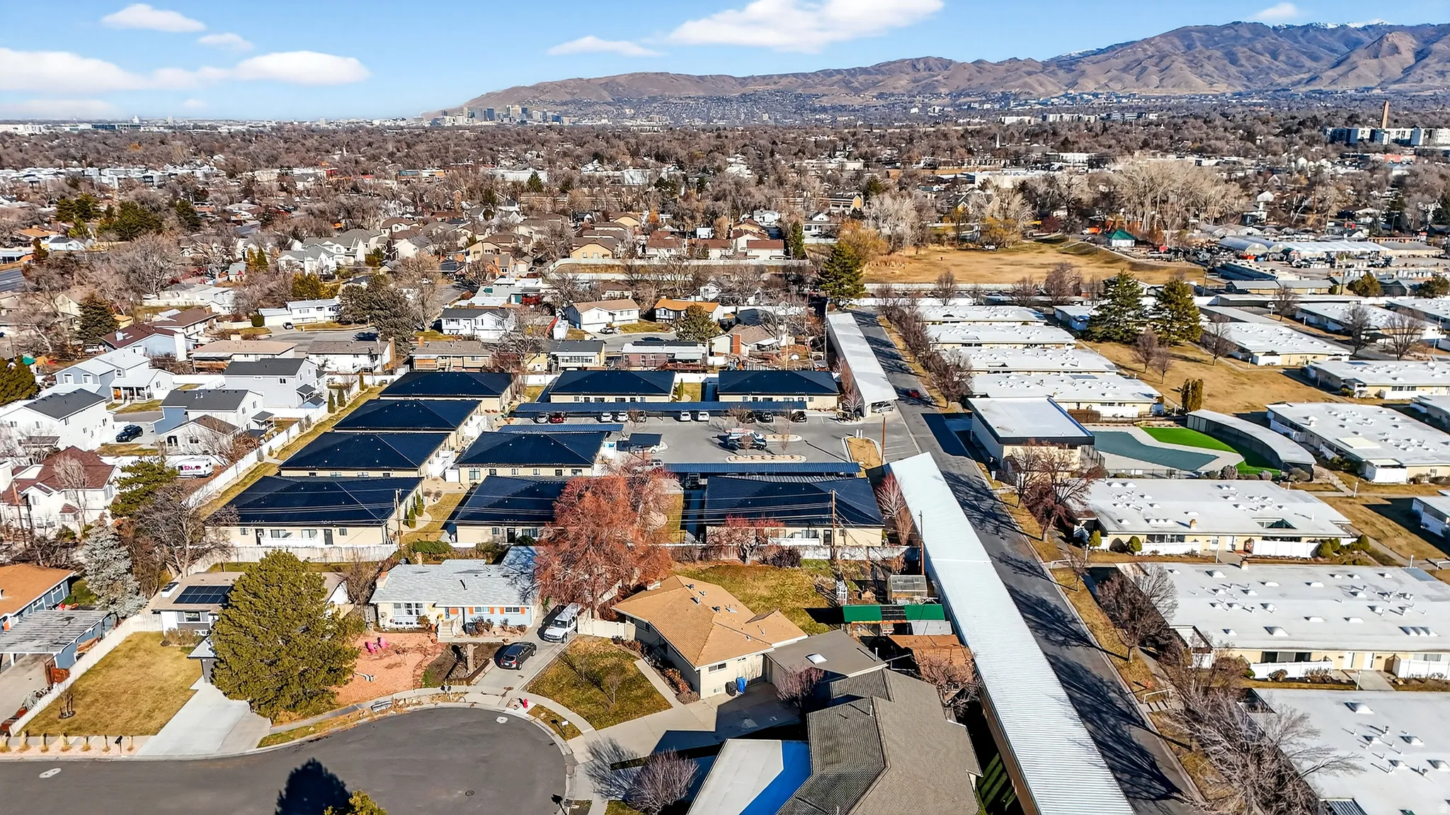 Aerial view of property and surrounding area featuring a mountainous background and nearby suburban area