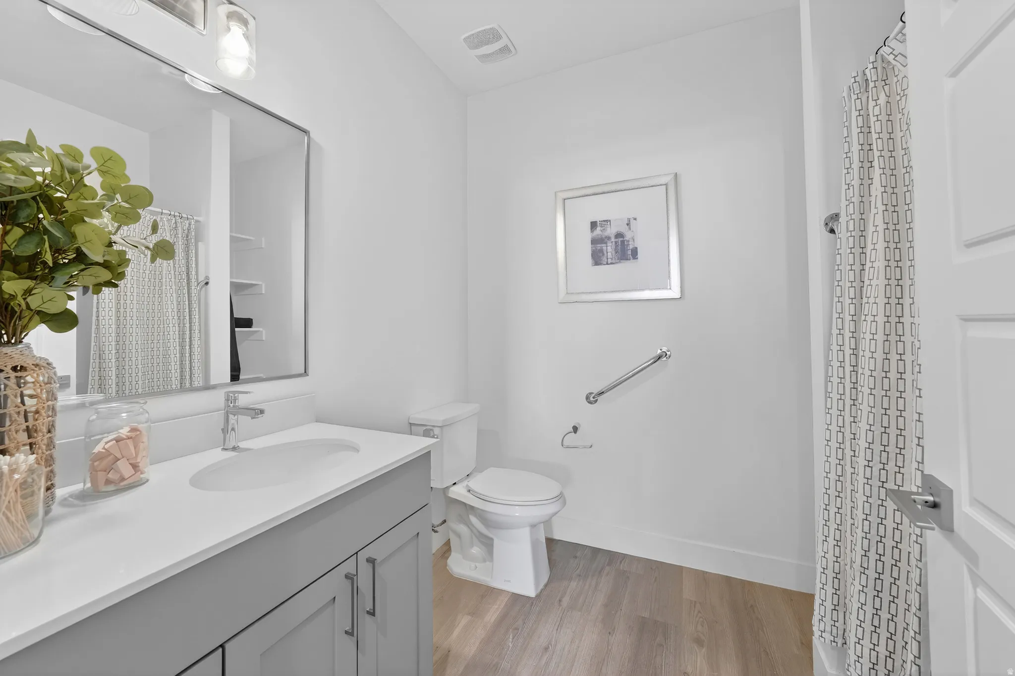 Bathroom featuring vanity, curtained shower, and light wood-style flooring