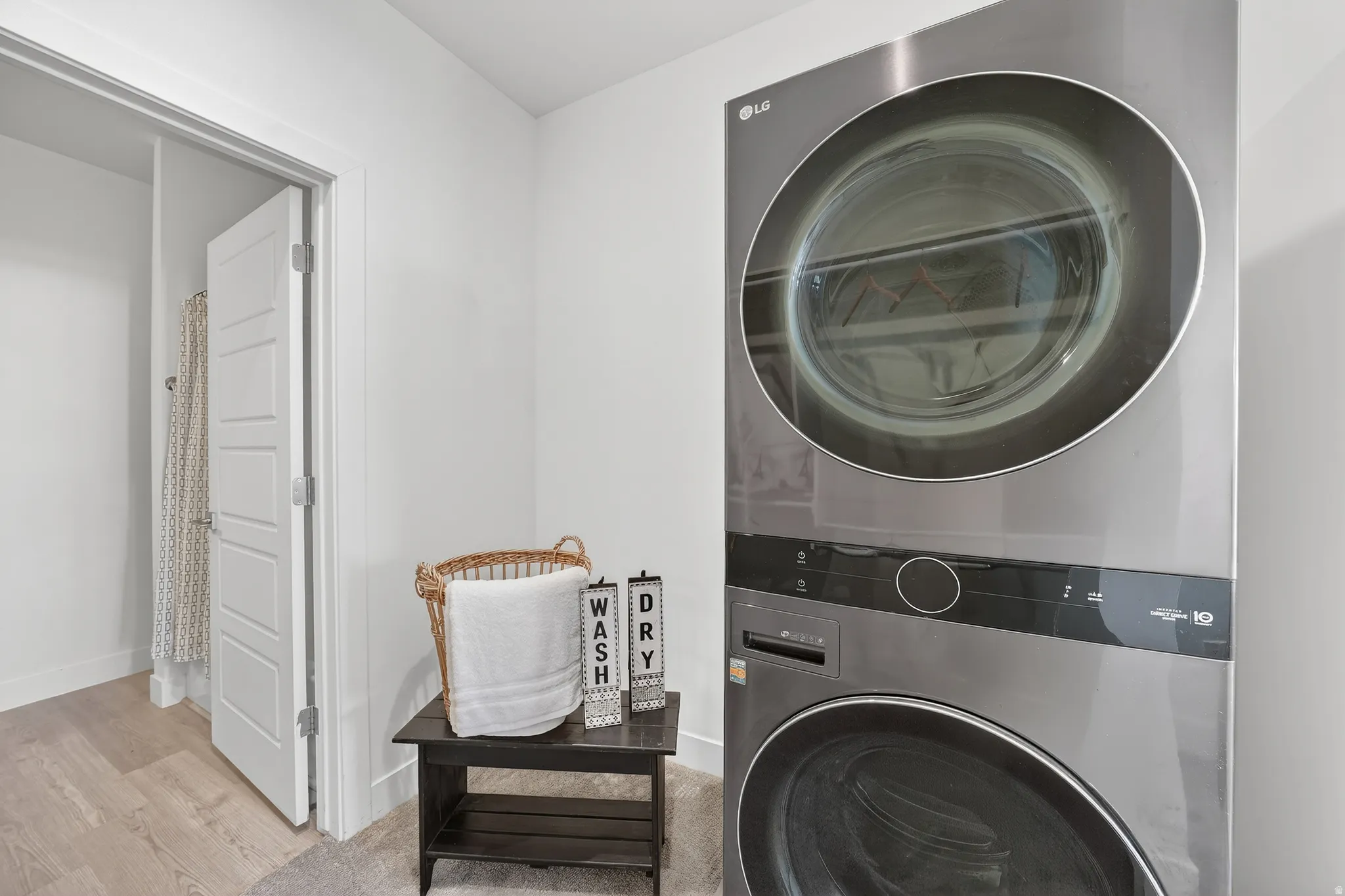 Laundry room with stacked washer and clothes dryer and wood finished floors