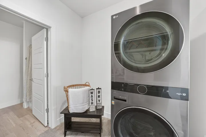 Laundry room with stacked washer and clothes dryer and wood finished floors