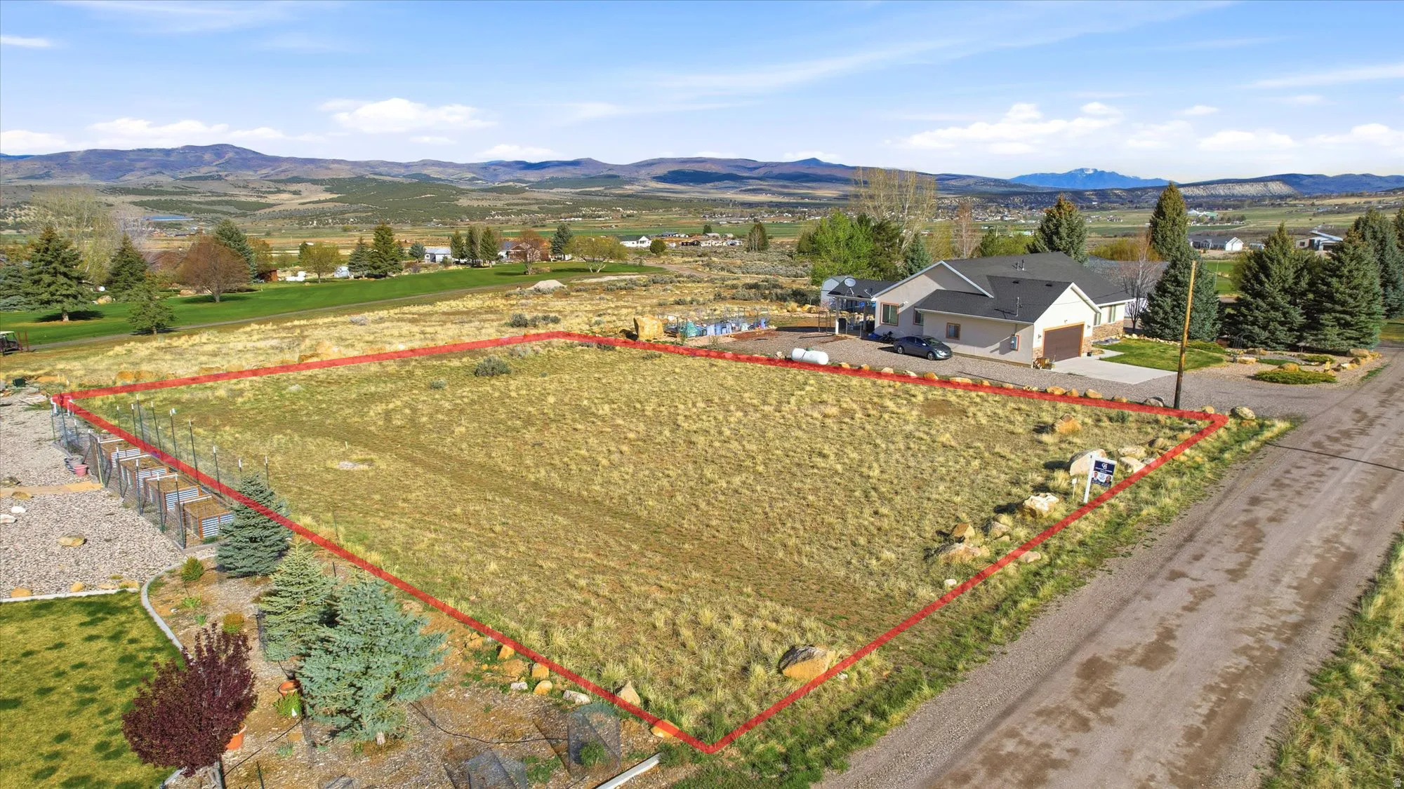 Expansive lot featuring a natural, undeveloped landscape, perimeter fencing, and distant mountain backdrops