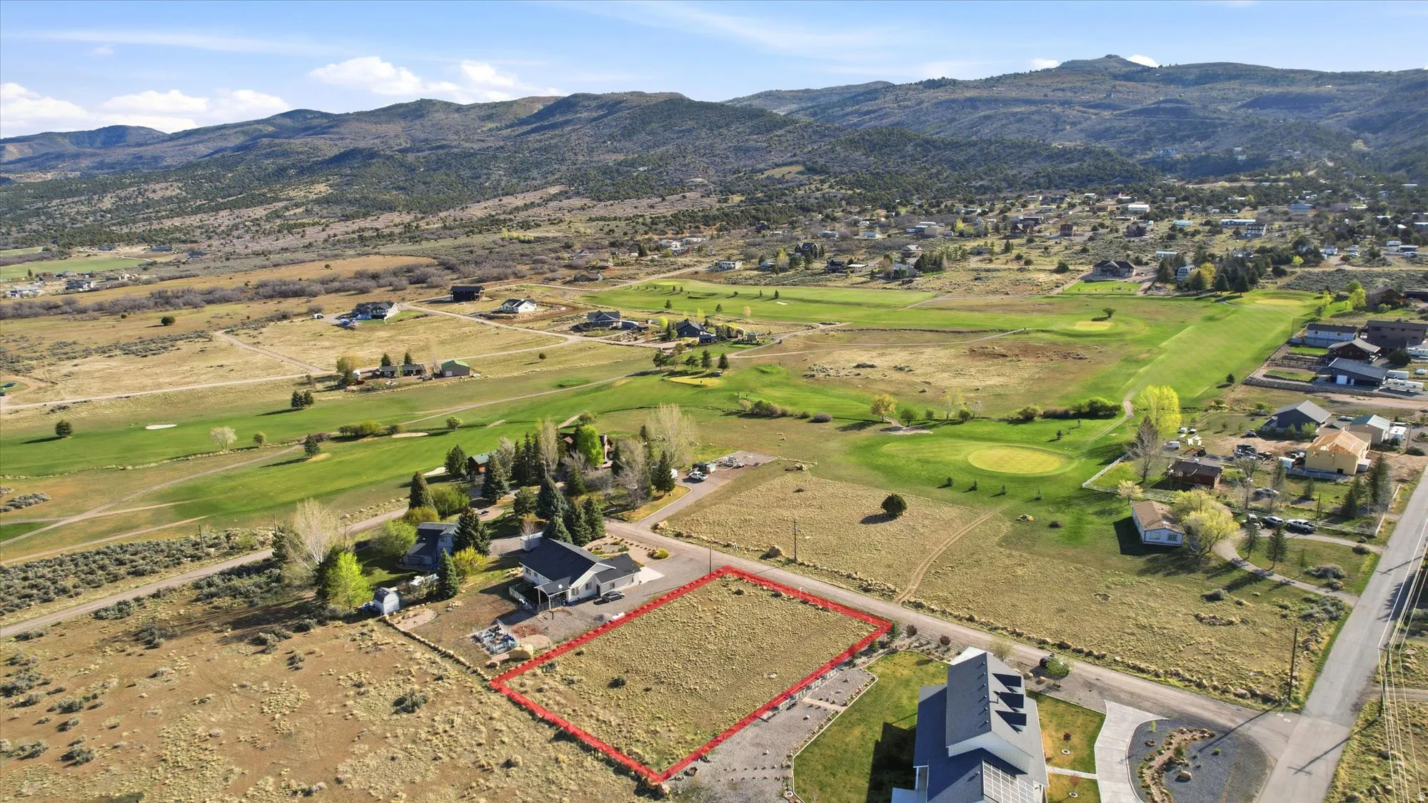 Expansive vacant lot featuring a defined perimeter, partially paved driveway, and established landscaping