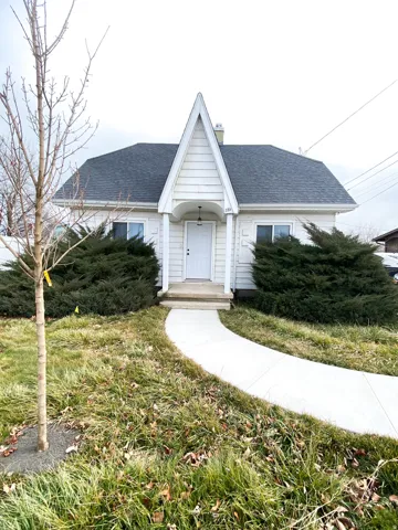 View of front of house featuring a shingled roof and a front lawn