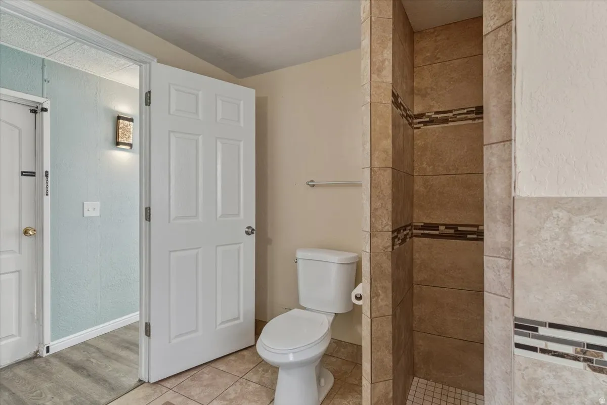 Bathroom with a stall shower, tile patterned flooring, and a textured wall
