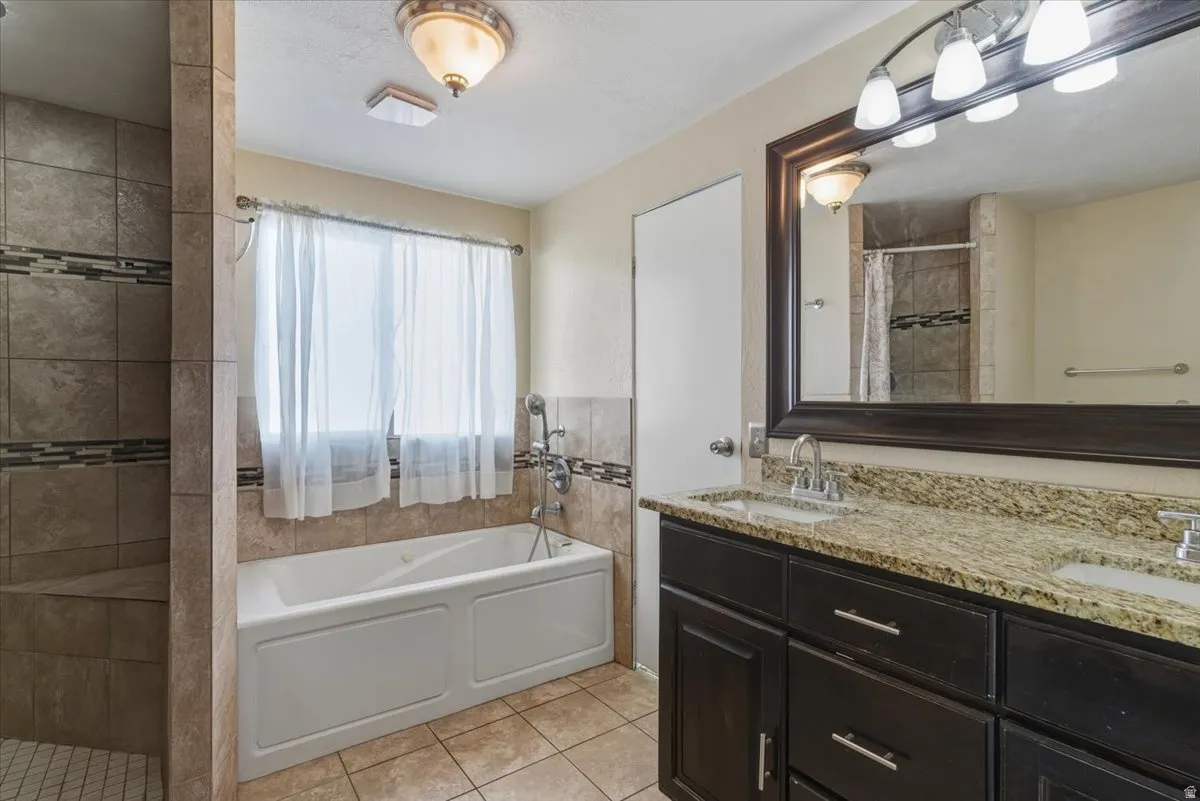Bathroom featuring a garden tub, a stall shower, double vanity, and light tile patterned floors