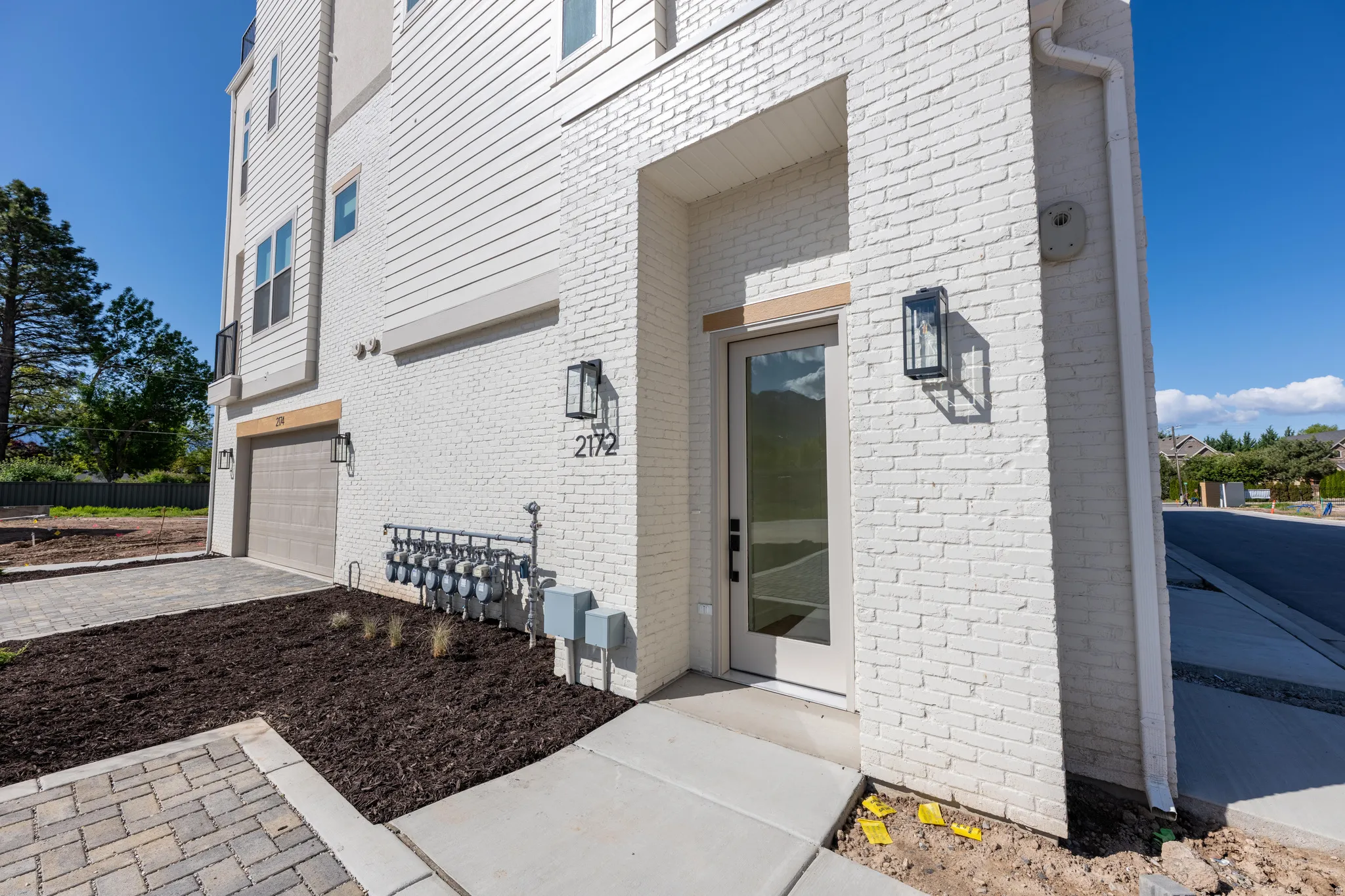 View of exterior entry with brick siding, an attached garage, and decorative driveway