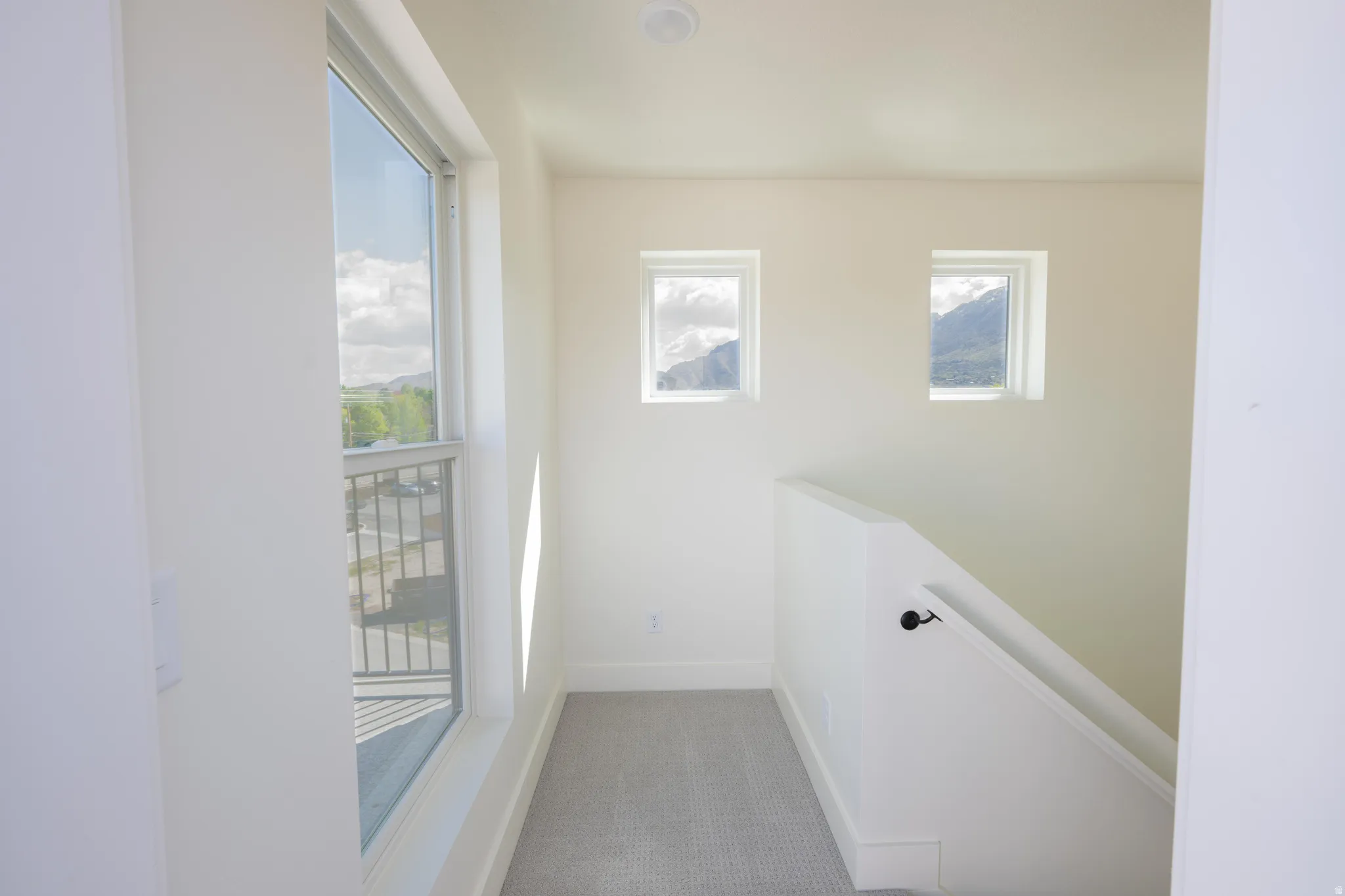 Corridor featuring an upstairs landing and light carpet