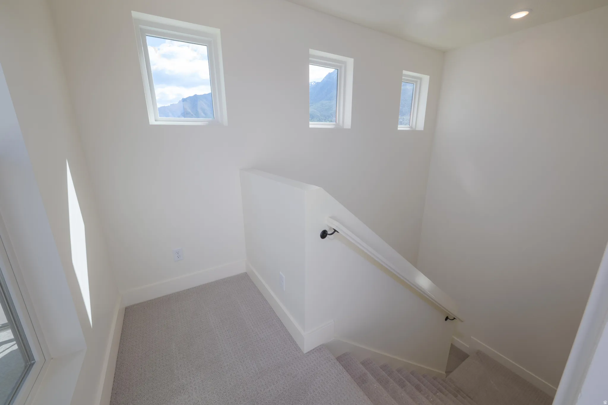 Stairway with healthy amount of natural light and carpet floors