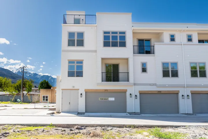 Back of house with a garage, a balcony, a mountain view, and stucco siding