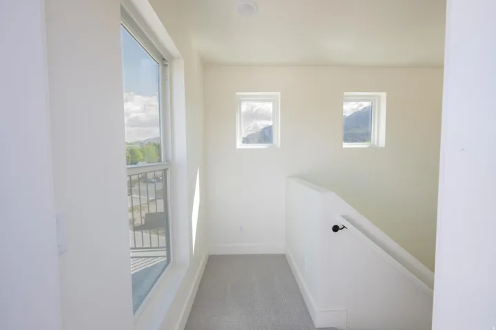 Corridor featuring an upstairs landing and light carpet