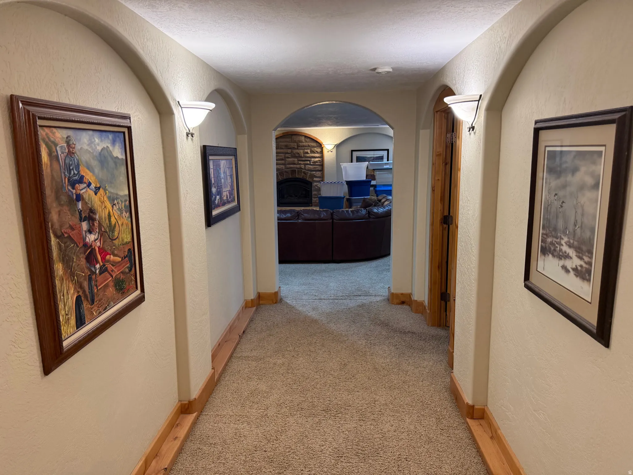 Corridor with a textured wall, light colored carpet, and arched walkways
