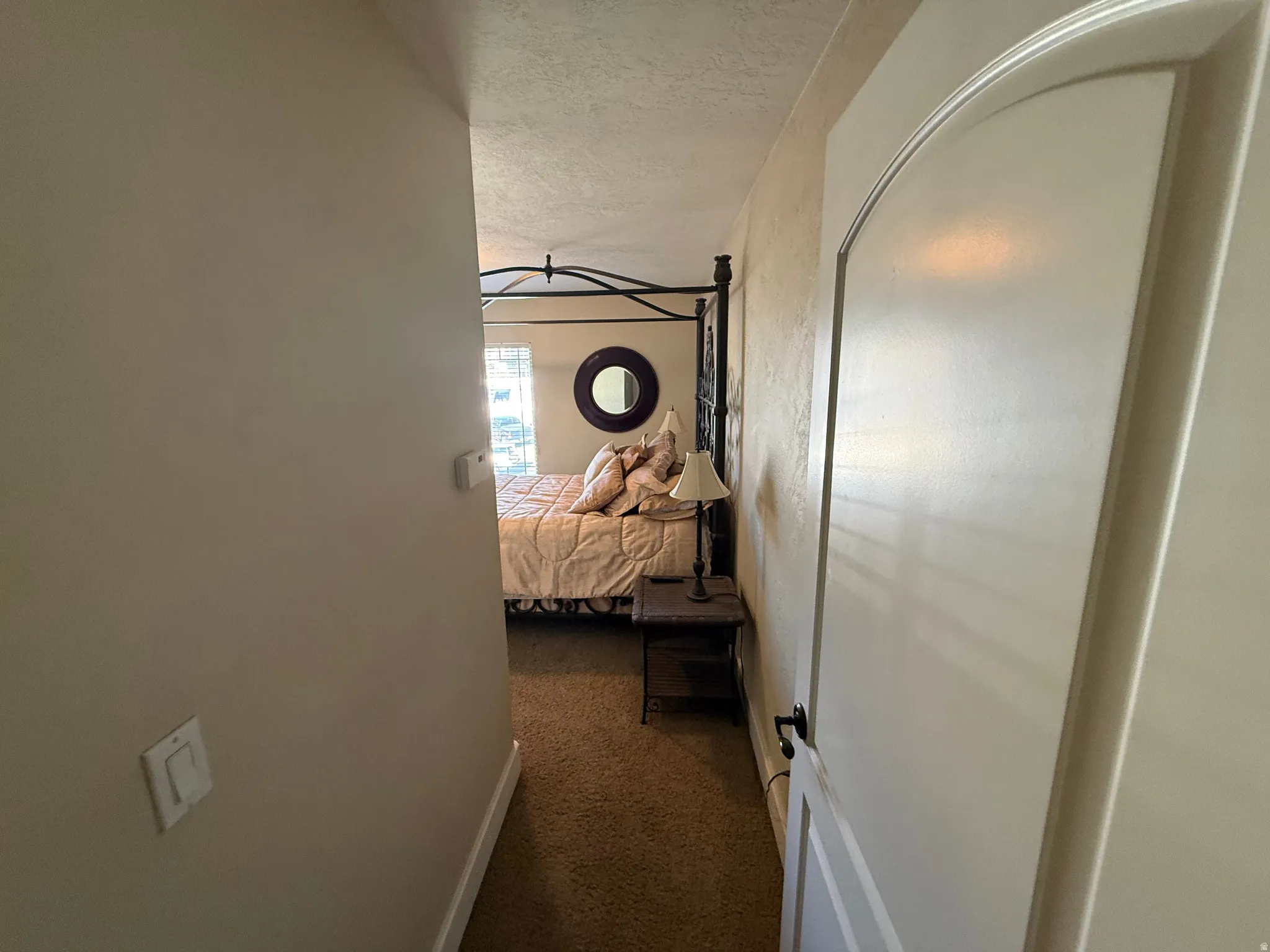 Corridor featuring dark colored carpet and a textured ceiling