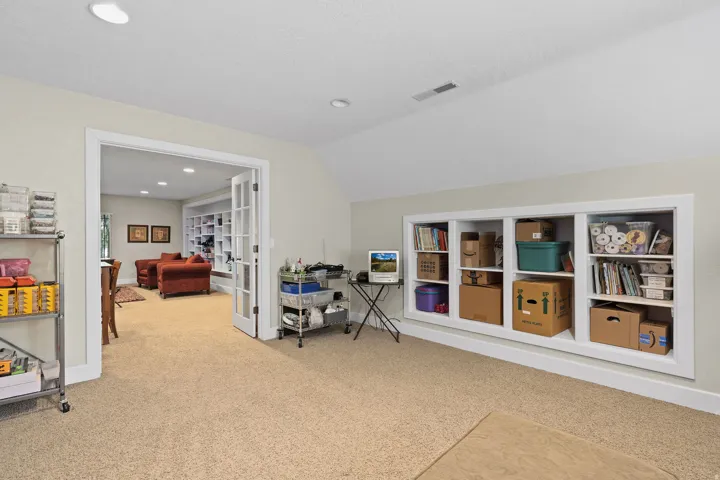 Recessed wall shelving with white trim, light-colored carpeting, recessed lighting, and a neutral wall color
