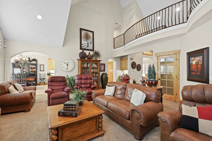 Expansive living area featuring vaulted ceilings, a prominent second-story balcony with decorative metal railing, and arched doorways
