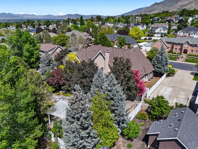 Aerial perspective showcasing a large property with a multi-gabled roofline, substantial mature landscaping, and a white pergola structure