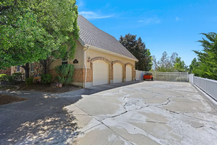 Stucco and brick exterior with a three-car garage featuring arched entryways