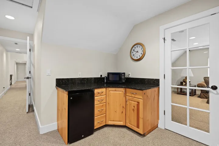 Compact kitchenette featuring light wood cabinetry, a dark countertop, and a built-in beverage refrigerator