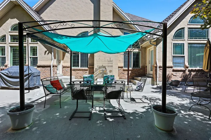 Spacious concrete patio featuring a metal pergola with a turquoise fabric shade