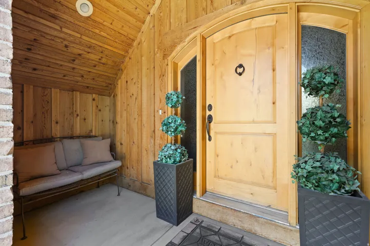Arched natural wood entry door with sidelight, complemented by wood-paneled walls and ceiling