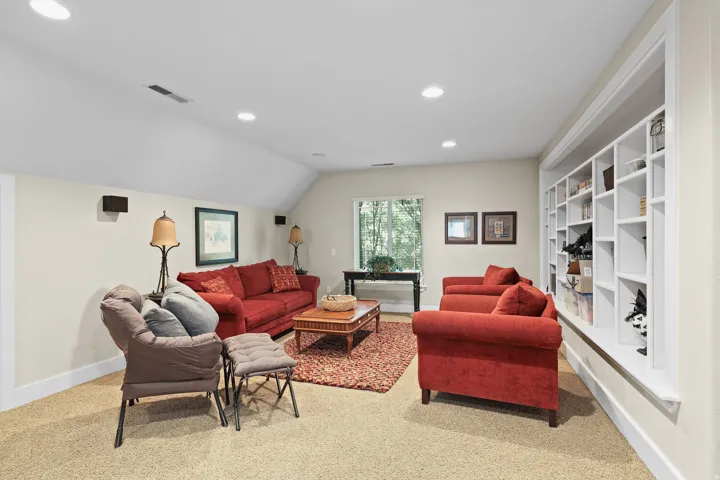 Carpeted living area featuring recessed lighting, a window, and a built-in shelving unit