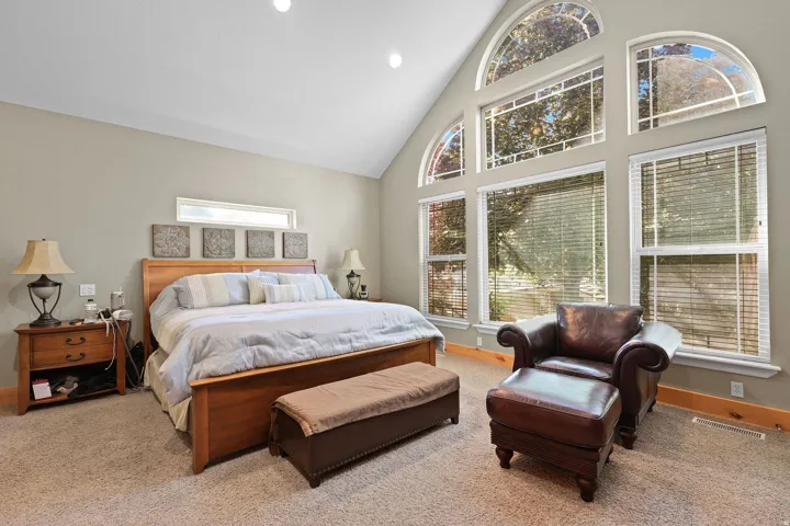 Vaulted ceiling bedroom featuring a full wall of windows with arched transom elements, recessed lighting, and soft carpet flooring