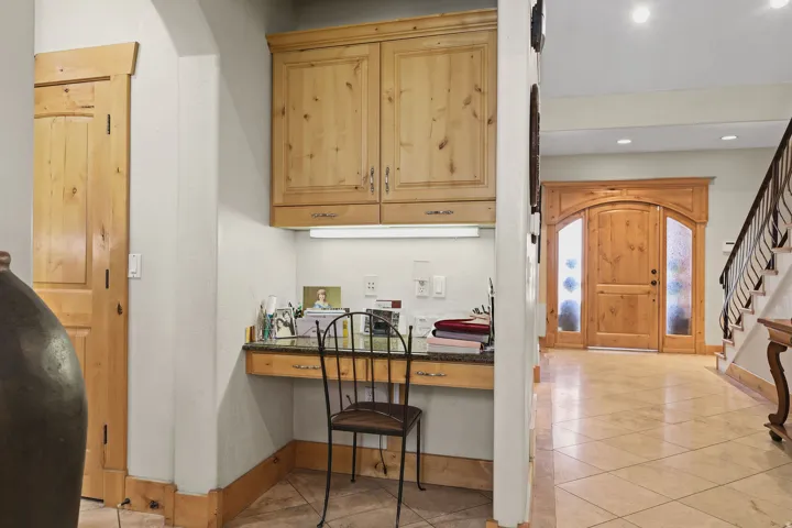 Built-in desk area featuring wood-finish cabinetry, under-cabinet lighting, and a stone-finish countertop