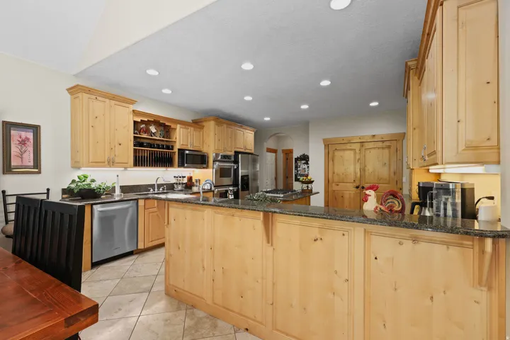 Spacious kitchen featuring light wood cabinetry, stainless steel appliances, granite countertops, and tile flooring