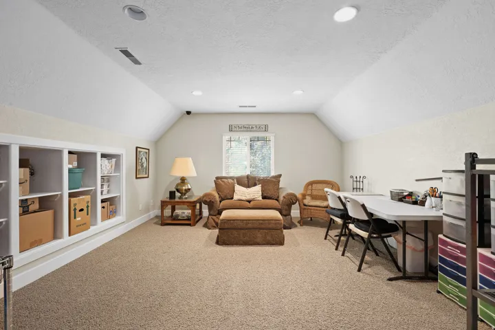 Versatile bonus room featuring vaulted ceilings, recessed lighting, built-in shelving, a window, and neutral carpeting