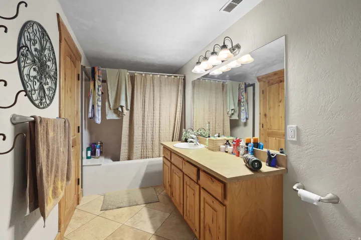 Bathroom featuring a light wood-finish vanity with ample storage, a single sink, and a large wall-mounted mirror