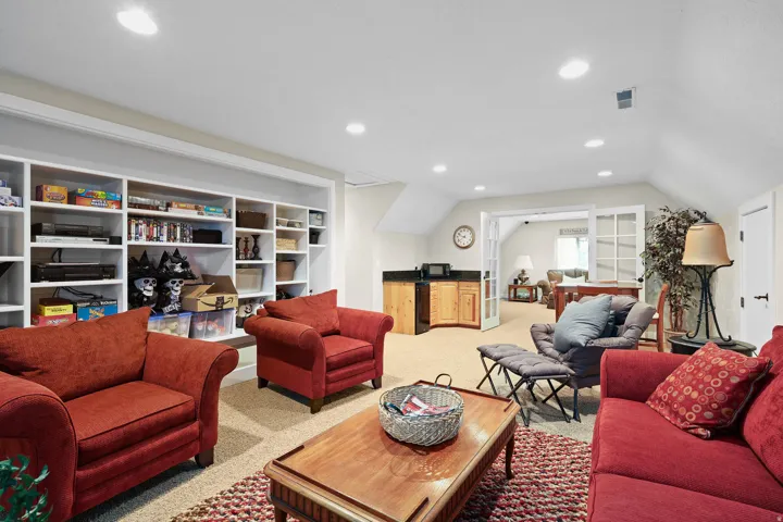 Spacious room featuring extensive built-in shelving, recessed lighting, and a wet bar with cabinetry