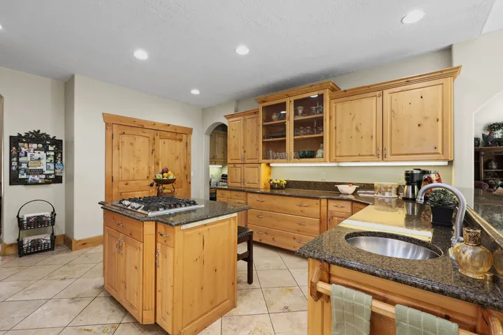 Kitchen featuring light wood cabinetry, recessed lighting, tile flooring, and dark granite countertops