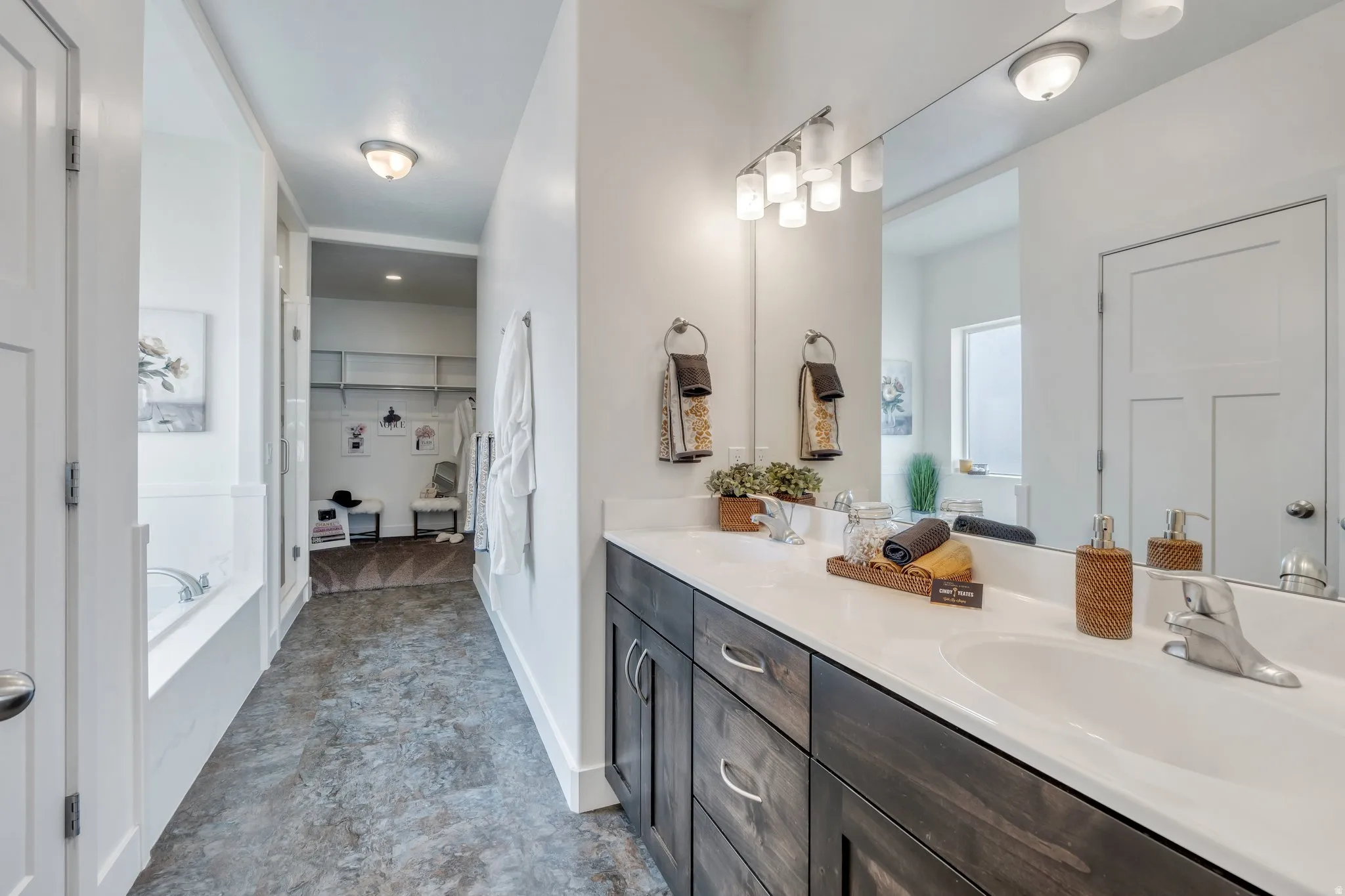 Full bathroom featuring double vanity, a spacious closet, and a garden tub