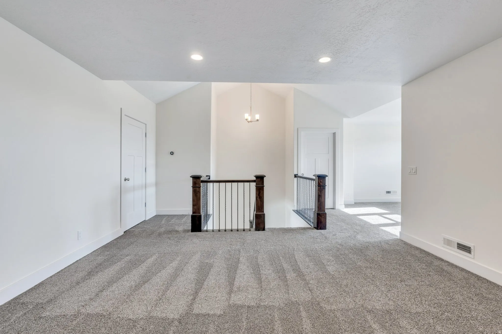 Carpeted spare room with vaulted ceiling and baseboards