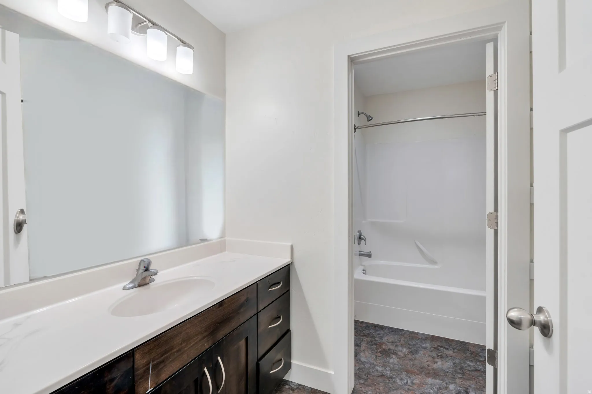 Bathroom with vanity, stone finish floors, and shower / washtub combination