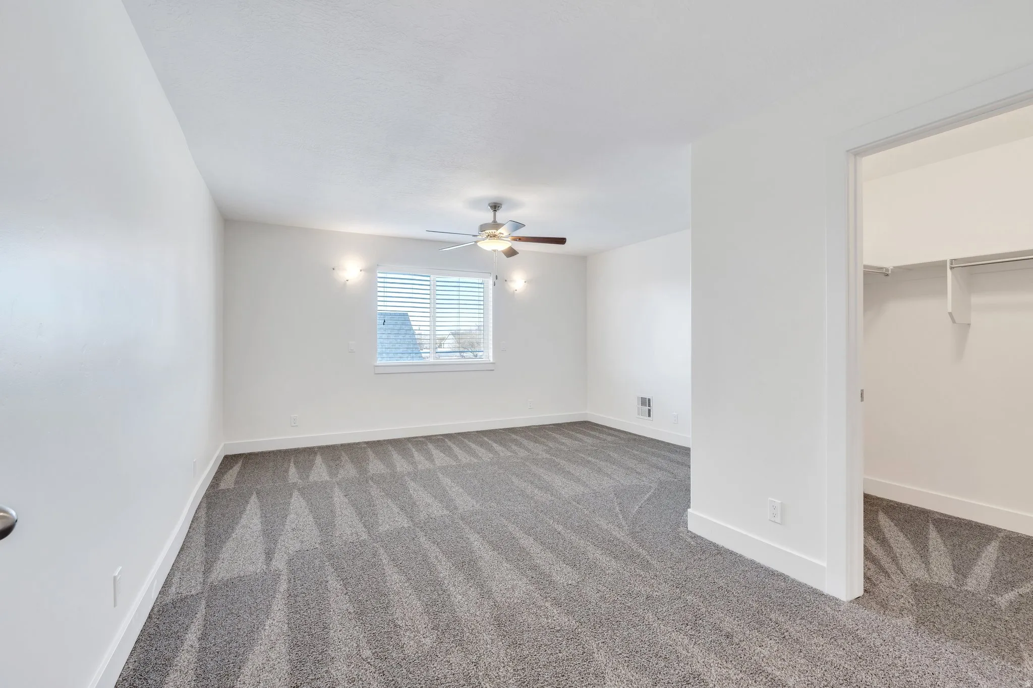 Unfurnished bedroom featuring carpet, a spacious closet, and ceiling fan