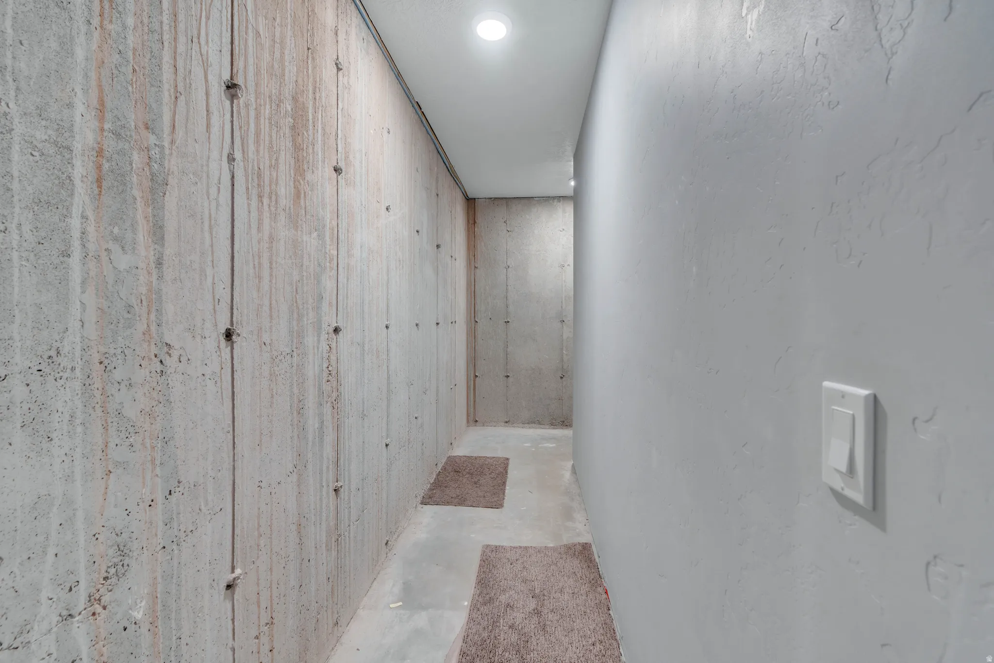 Corridor with unfinished concrete flooring and recessed lighting