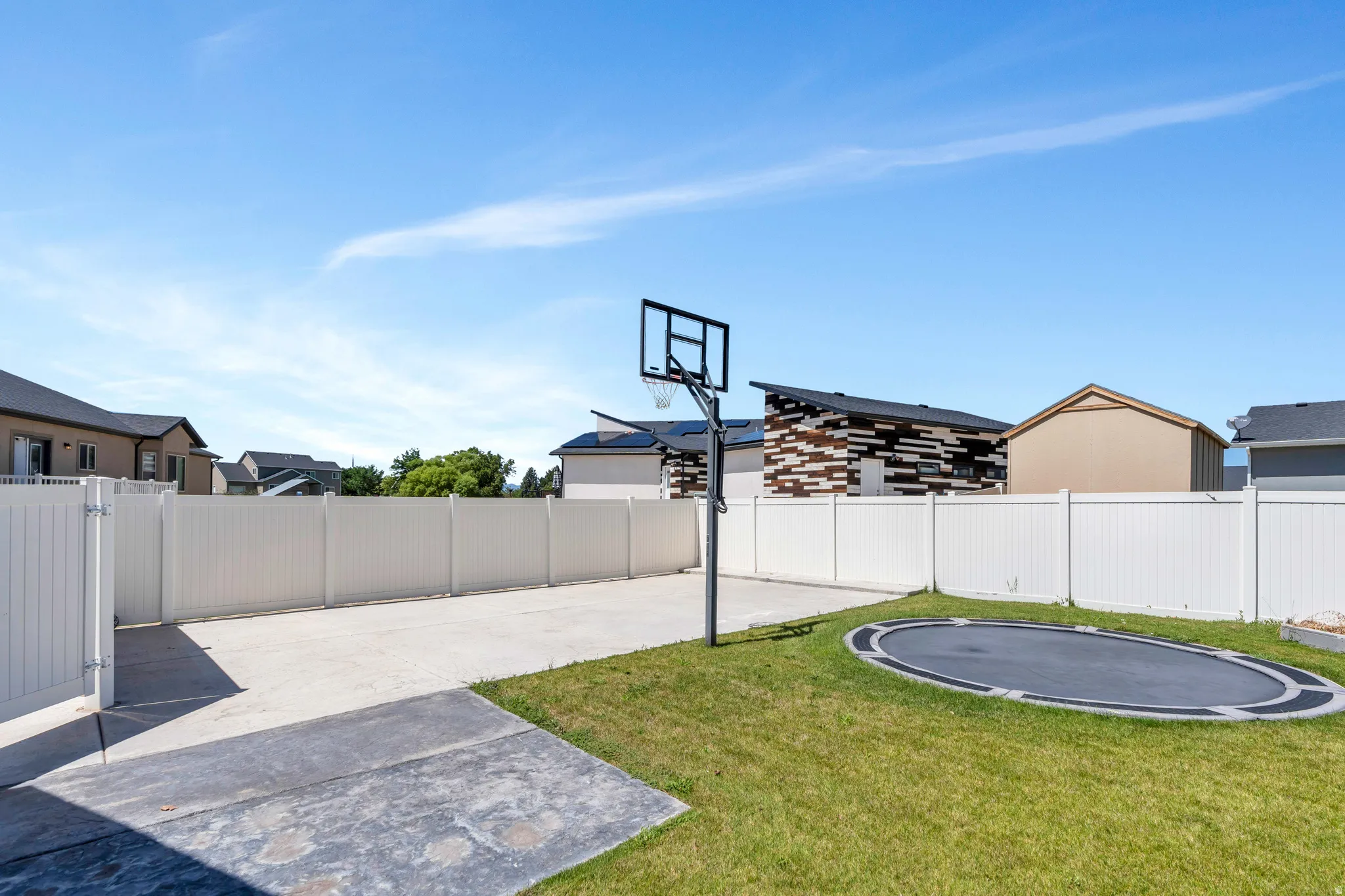 View of sport court with a trampoline, a fenced backyard, and basketball court