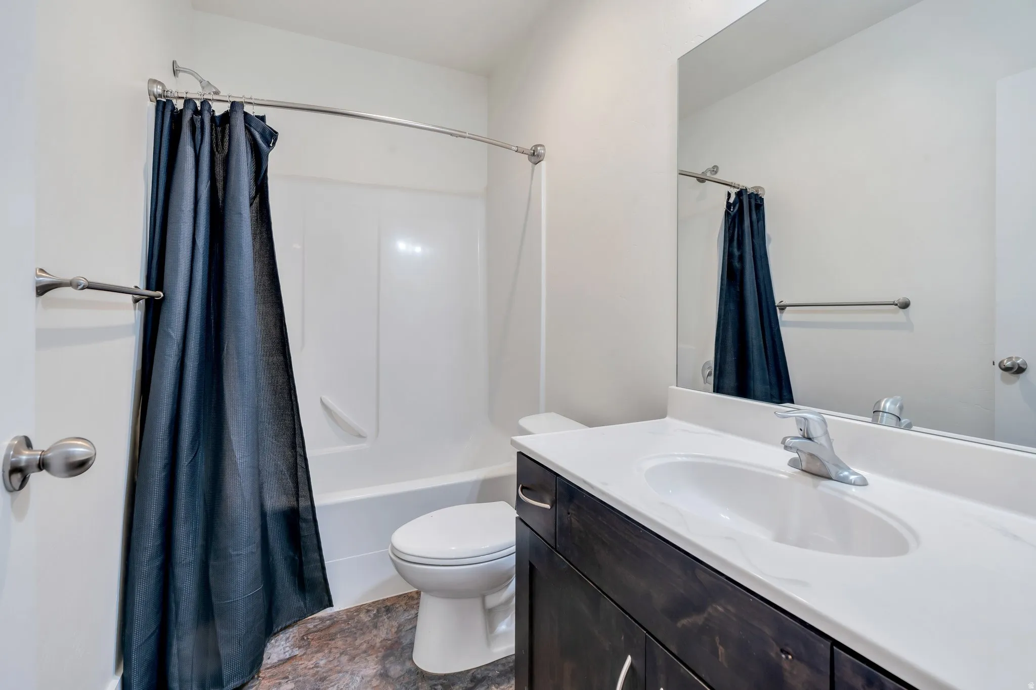 Bathroom featuring vanity, stone finish flooring, and shower / bath combo